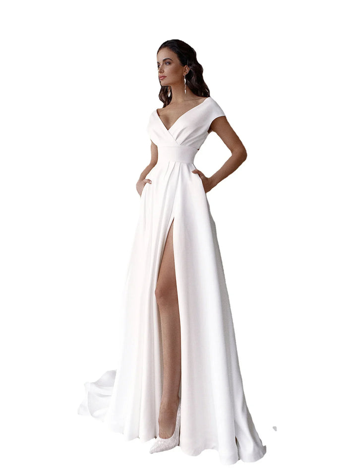 Elegant woman in white evening gown with off-shoulder neckline and high slit posing