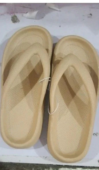 Pair of beige eco-friendly foam slippers with textured soles on white surface