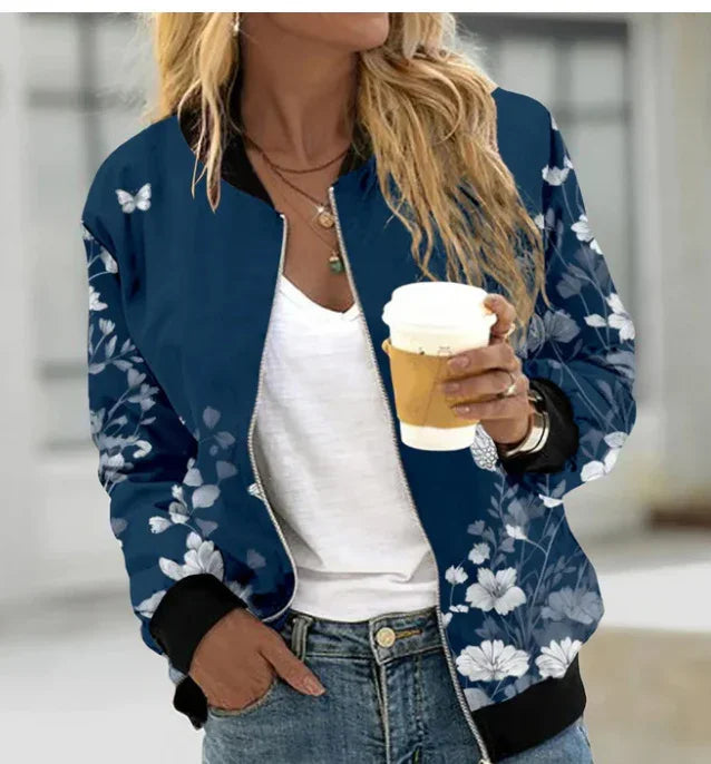 Woman wearing a navy blue floral bomber jacket with black cuffs, holding a coffee cup, casual outfit