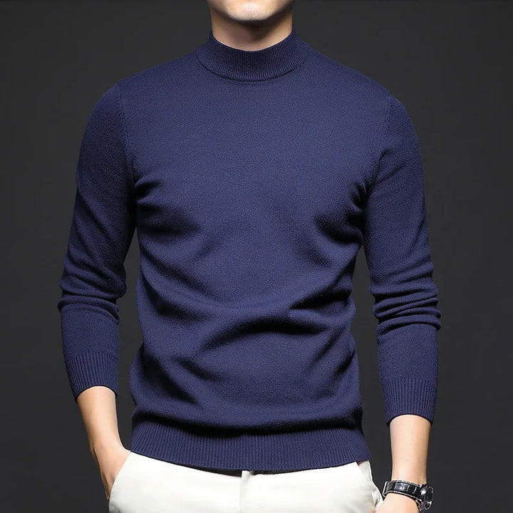 man wearing fitted navy blue turtleneck sweater with white pants and black wristwatch