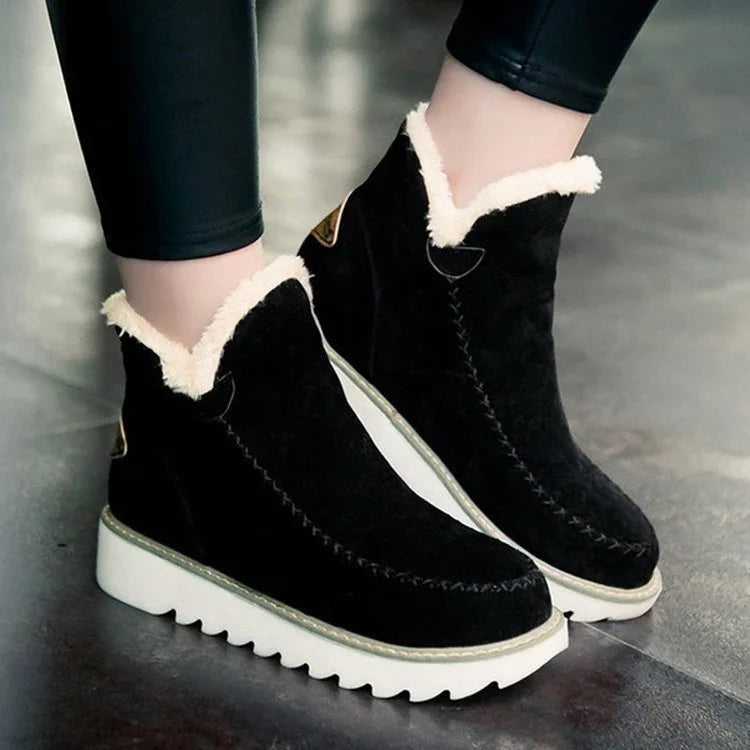 Black suede ankle boots with white fleece lining and thick white ridged soles worn with black leggings