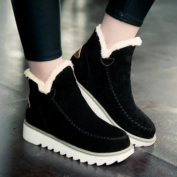 Black suede ankle boots with white fleece lining and thick white ridged soles worn with black leggings