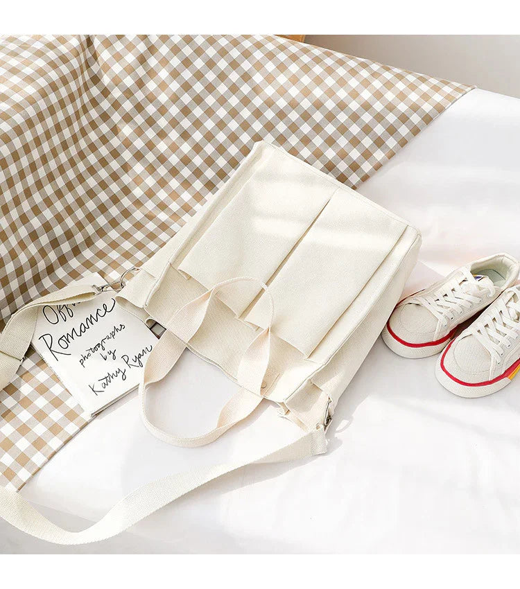 Cream canvas tote bag with front pockets, beige gingham fabric, and white canvas sneakers with red and yellow stripes