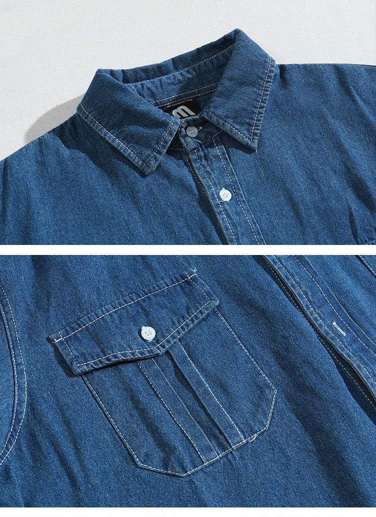 Close-up of blue denim shirt collar and buttoned chest pocket with detailed stitching