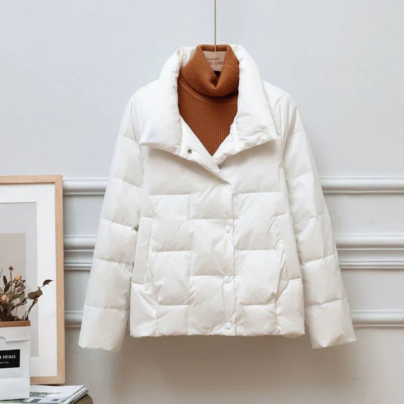 White quilted puffer jacket displayed on a hanger with a brown turtleneck sweater inside