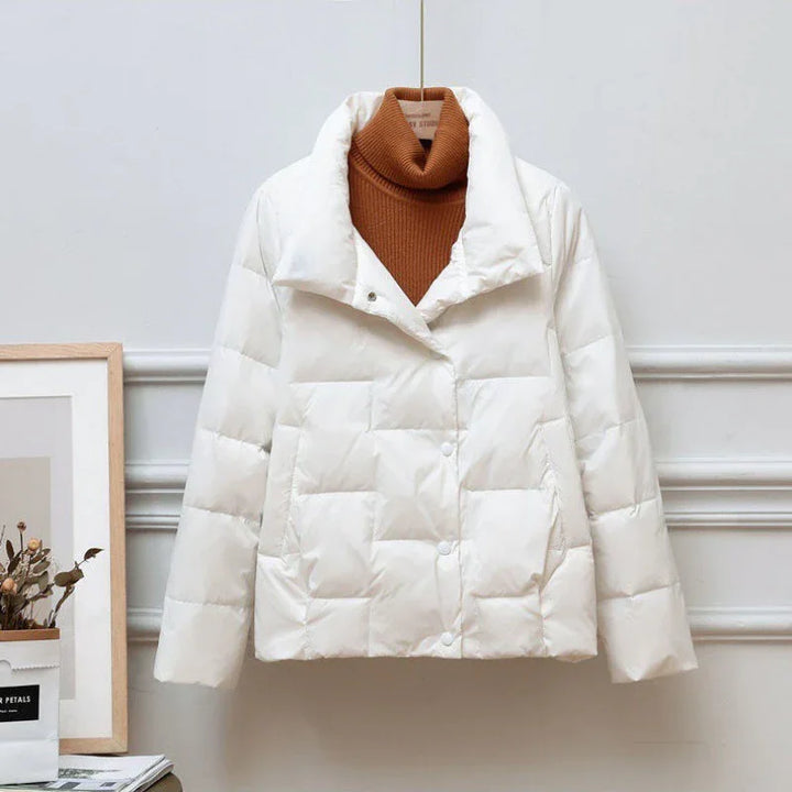 White quilted puffer jacket displayed on a hanger with a brown turtleneck sweater inside