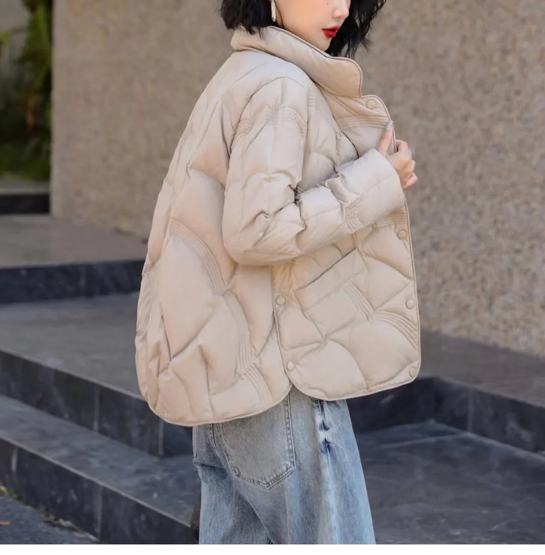 Woman wearing beige quilted puffer jacket with wide collar and light blue jeans outdoors