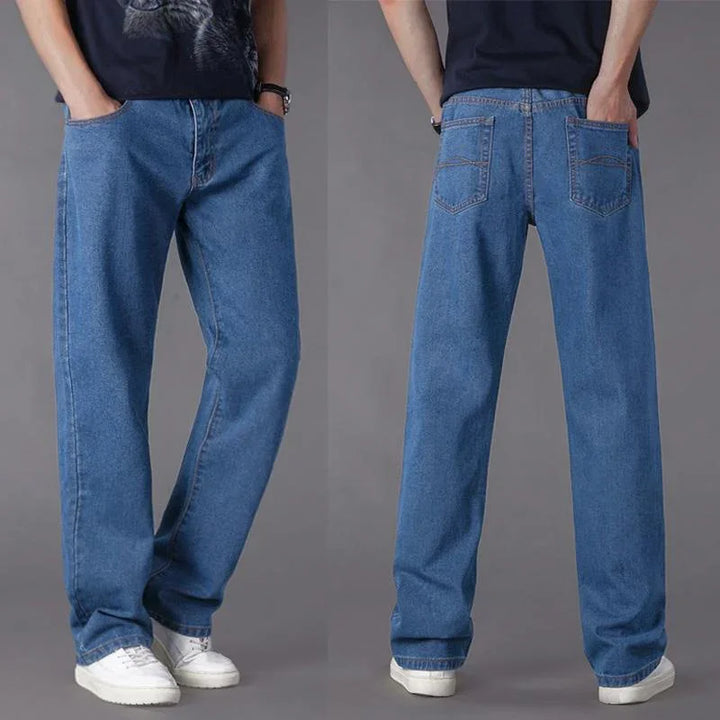 Front and back views of relaxed fit blue denim jeans worn with white sneakers against a gray background