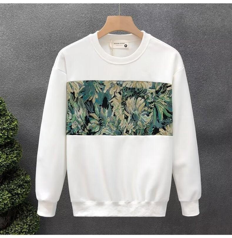 White sweatshirt with floral tapestry panel across chest on wooden hanger against gray background