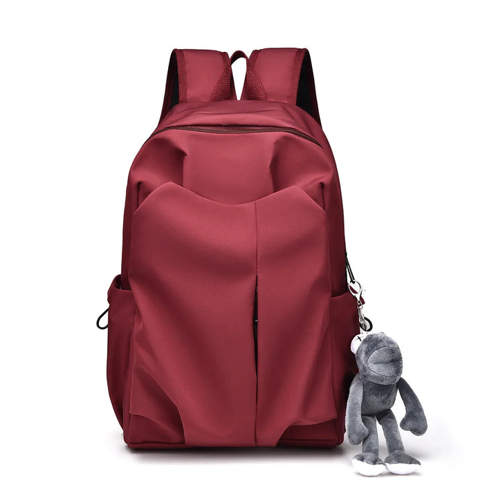 Red school backpack with front pockets and a hanging gray plush toy keychain