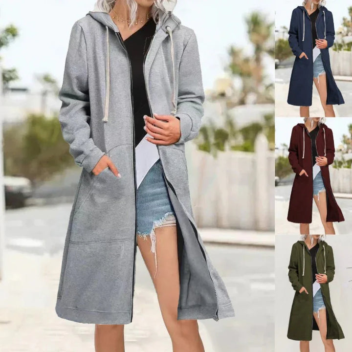 Woman wearing a long hooded zip-up cardigan in gray, navy, maroon, and green with pockets outdoors