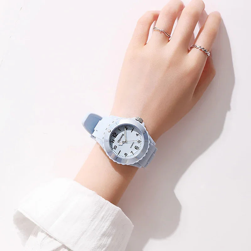 Close-up of wrist wearing a light blue silicone quartz watch and two silver rings on fingers