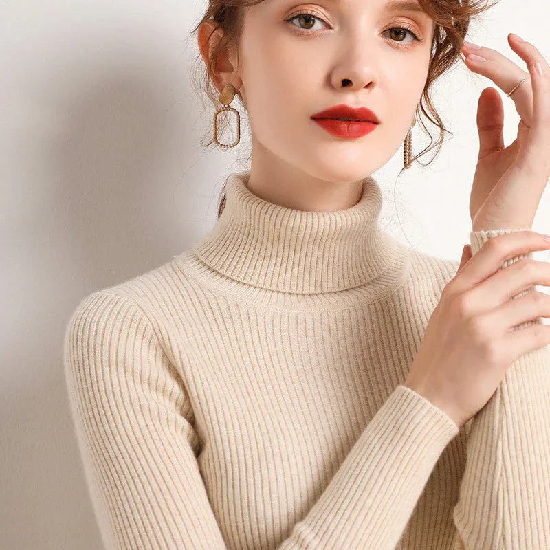 Woman wearing beige ribbed turtleneck sweater and gold statement earrings with red lipstick
