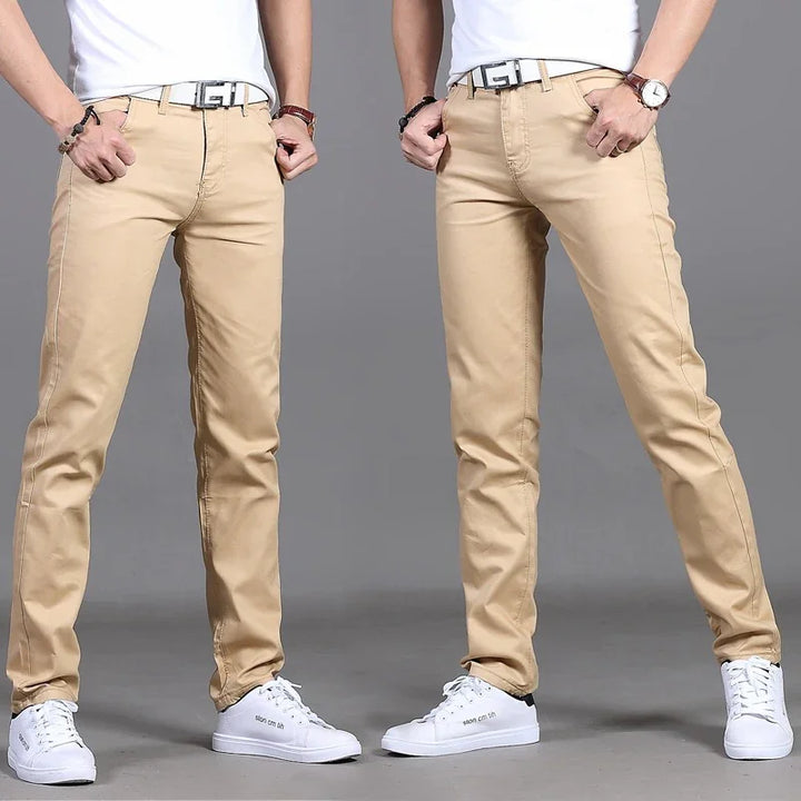Men wearing beige slim-fit pants with white sneakers and white t-shirts on gray background