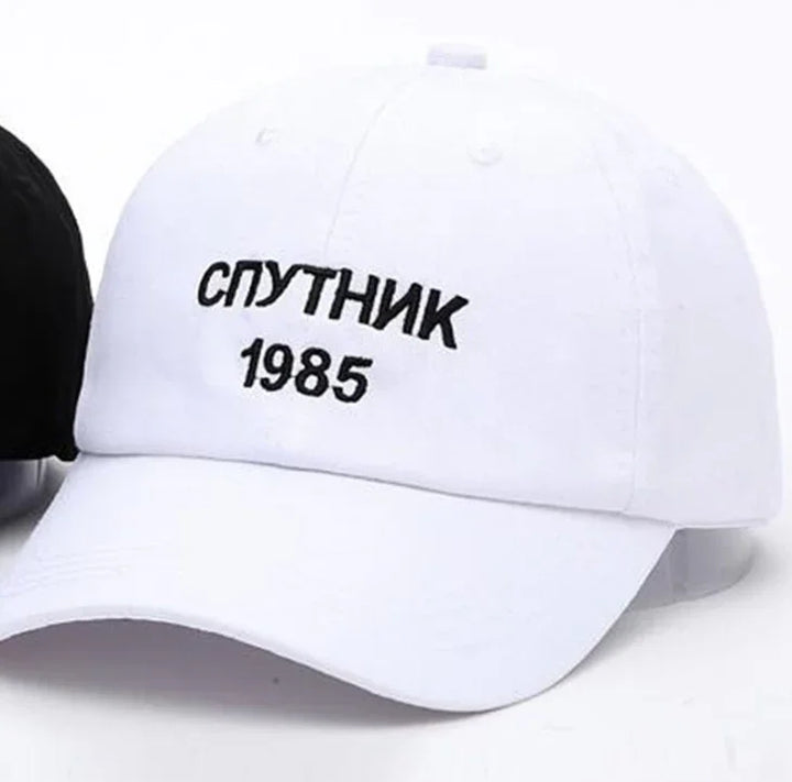 White baseball cap with black embroidered text 'СПУТНИК 1985' on front panel