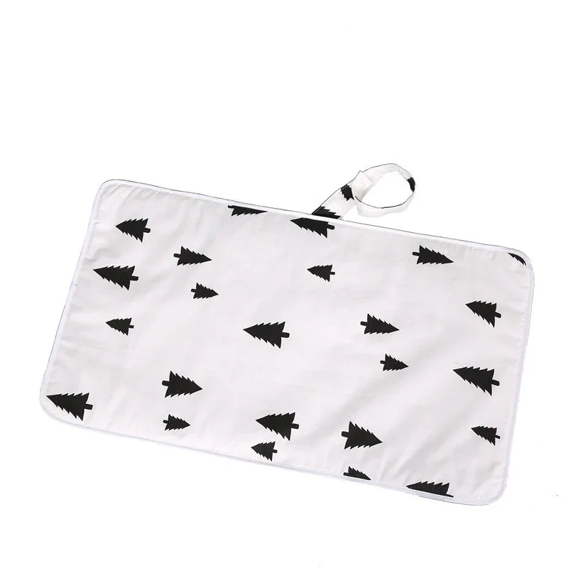 White rectangular changing mat with black pine tree pattern and carrying strap