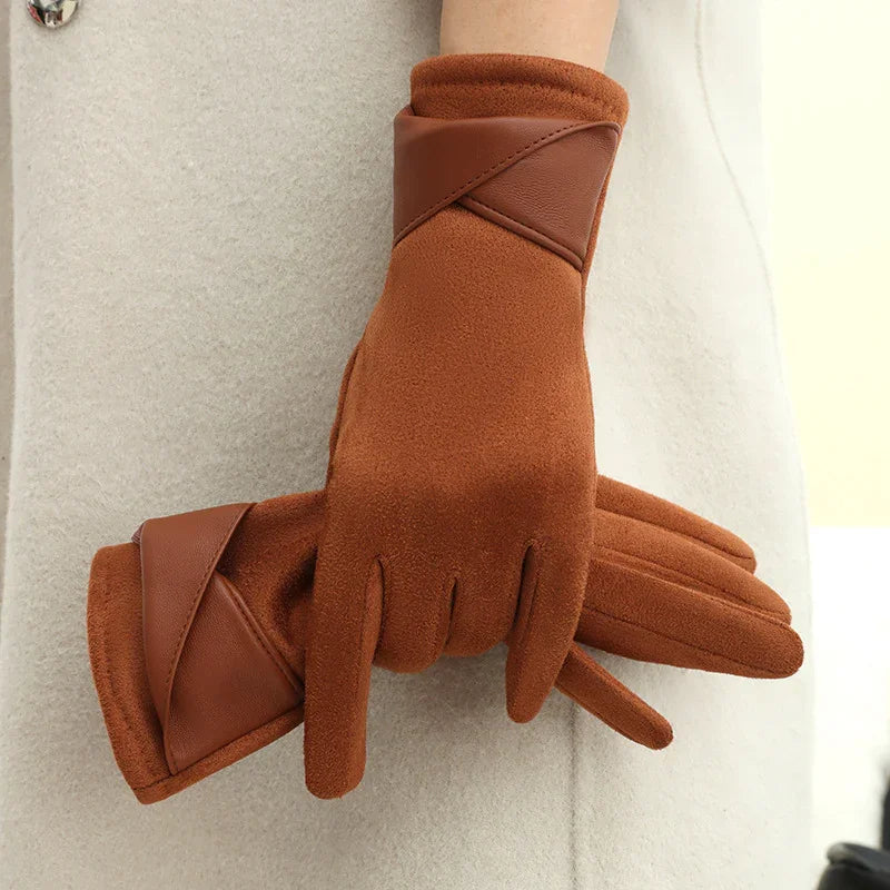 Brown fleece winter gloves with leather accents worn on hands against a beige coat background