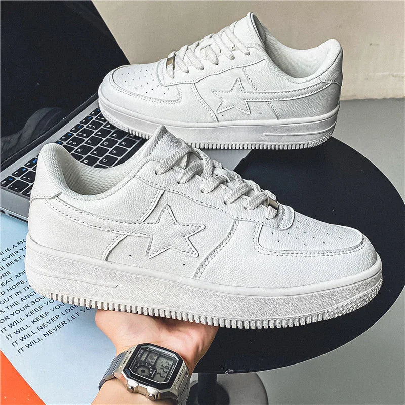 Pair of white leather sneakers with star detail on black round table and laptop background