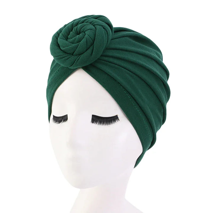 Dark green turban headwrap with rose detail on a white mannequin head