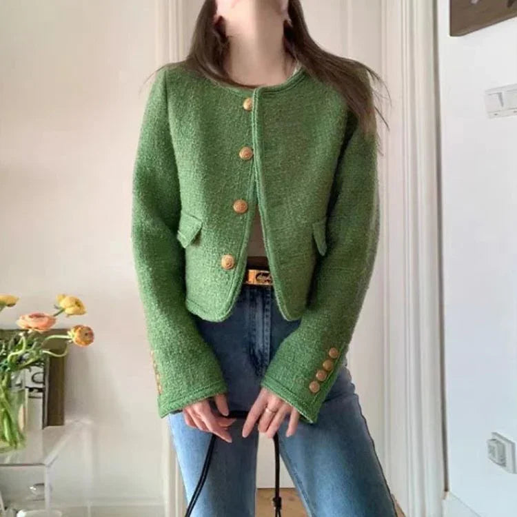 Woman wearing a green textured buttoned cardigan with flared sleeves and blue jeans indoors
