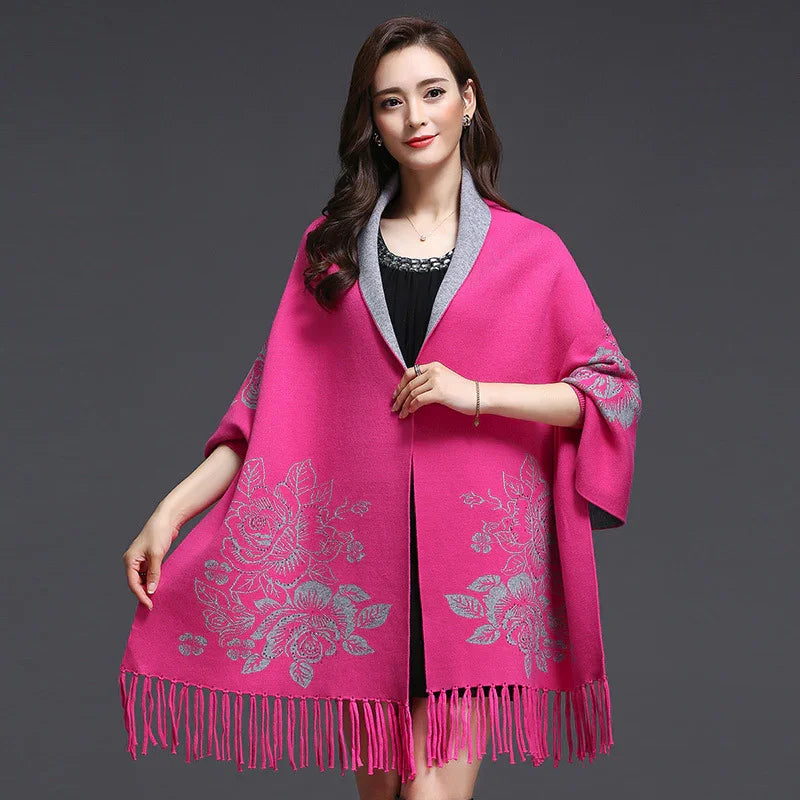 Woman wearing bright pink floral embroidered shawl with fringe over black dress on gray background