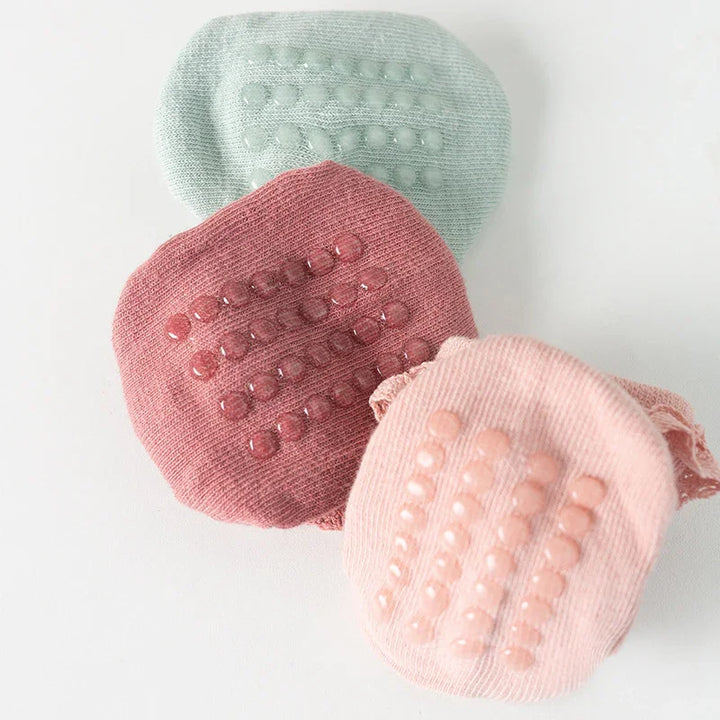 Close-up of three pastel-colored silicone scrubbers with textured grips on a white surface
