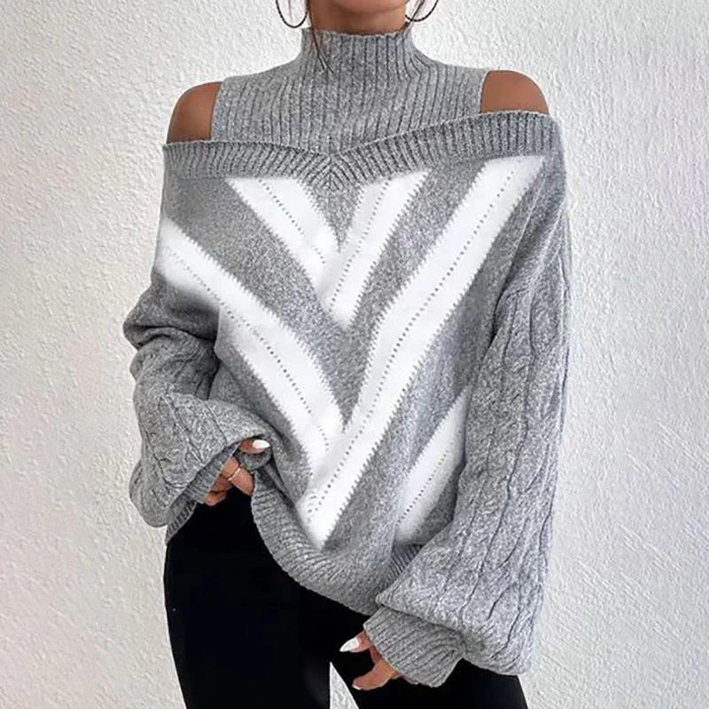 Woman wearing gray cold shoulder knit sweater with white chevron pattern and black pants