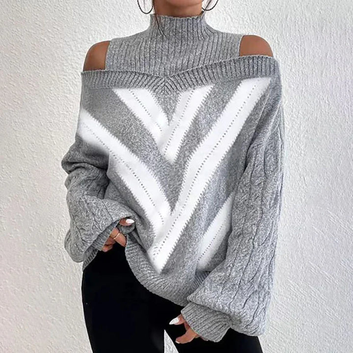 Woman wearing gray cold shoulder knit sweater with white chevron pattern and black pants