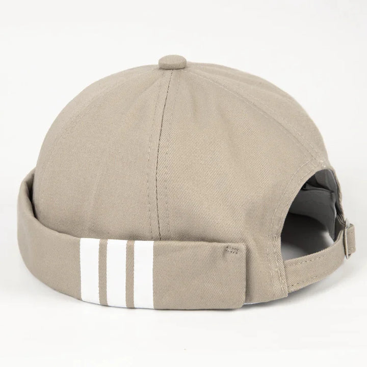 Beige cotton cap with folded brim and three white stripes, adjustable back strap visible