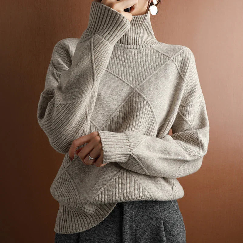 Woman wearing beige oversized turtleneck knit sweater with textured pattern and ribbed cuffs