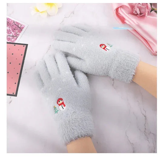 Soft gray winter gloves with embroidered snowman design on white marble surface