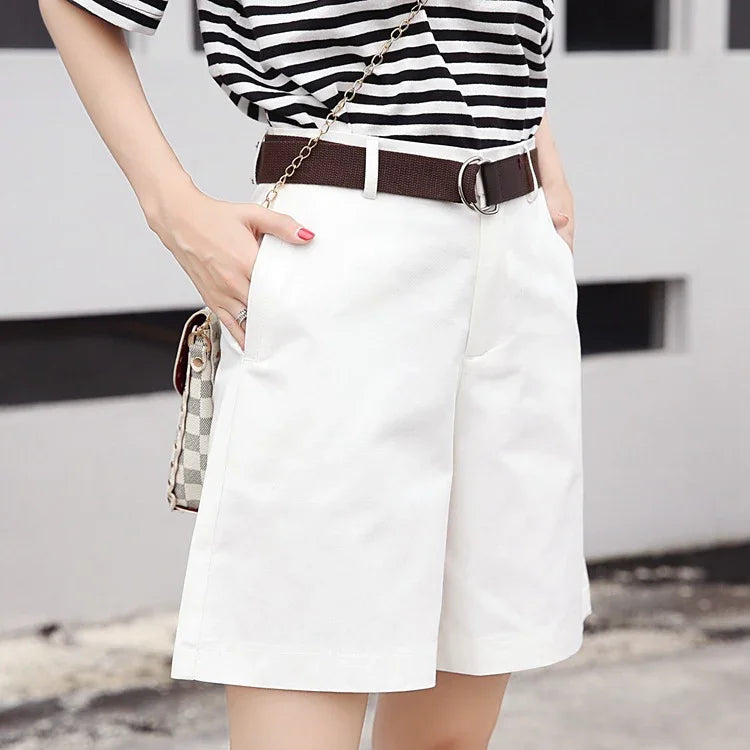 Woman wearing white knee-length shorts with brown belt and black-and-white striped top