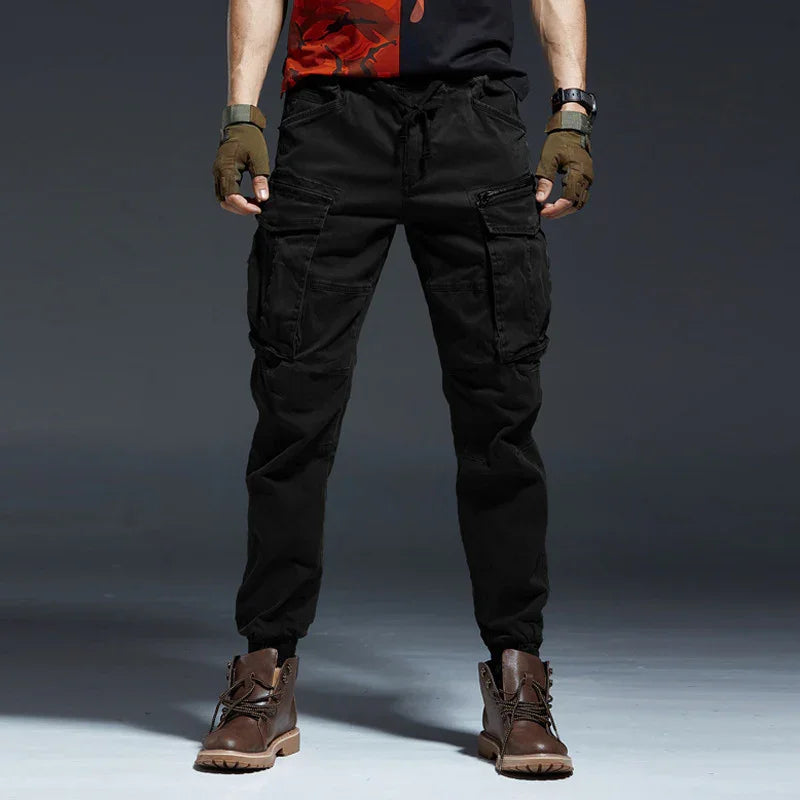 Men's black cargo pants with multiple pockets paired with brown boots and fingerless gloves