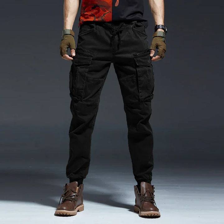 Men's black cargo pants with multiple pockets paired with brown boots and fingerless gloves