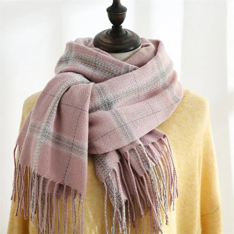 Soft pink plaid wool scarf with fringe on a yellow sweater displayed on a mannequin