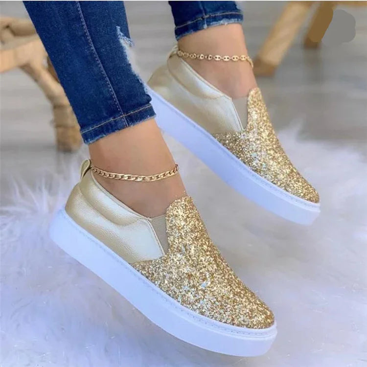 Women wearing gold glitter slip-on sneakers with white soles and gold anklets, paired with blue jeans