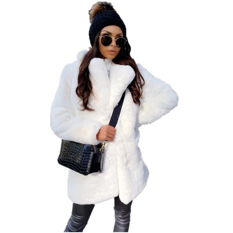 Woman wearing white faux fur coat, black knit beanie with pom-pom, sunglasses, and black leather pants