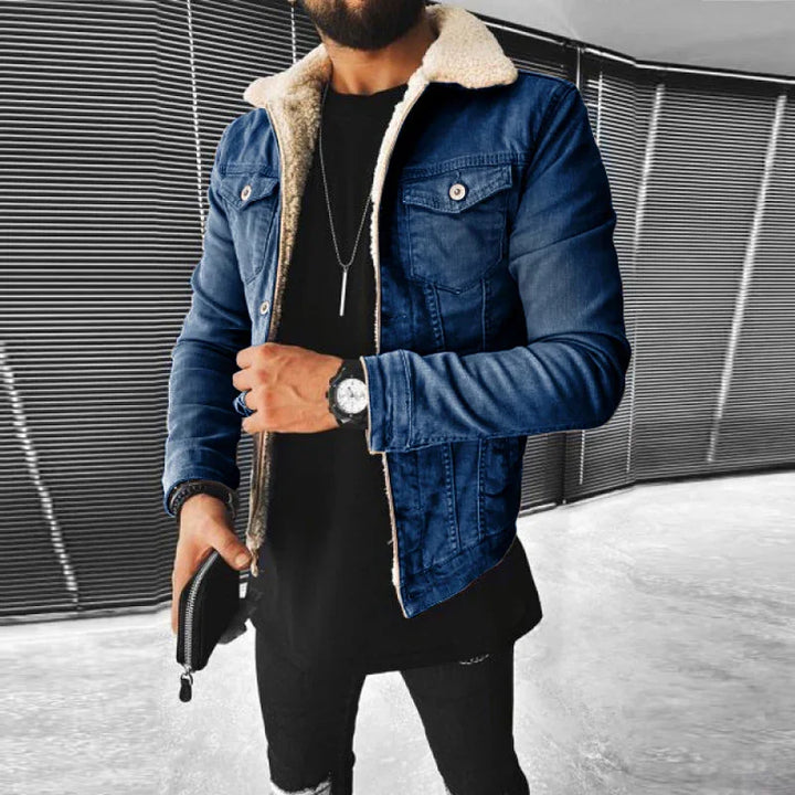Man wearing a blue denim jacket with white fleece lining, black shirt, and accessories holding a black wallet