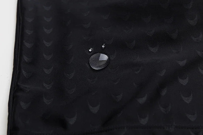 Close-up of water droplets on black textured waterproof fabric with subtle pattern