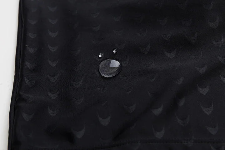 Close-up of water droplets on black textured waterproof fabric with subtle pattern