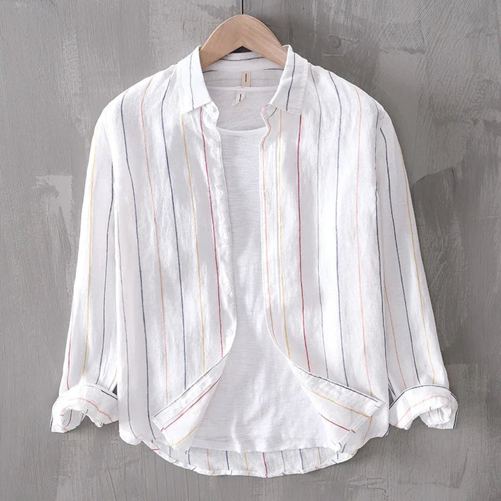 White long-sleeve button-up shirt with multicolor vertical stripes on wooden hanger against gray wall