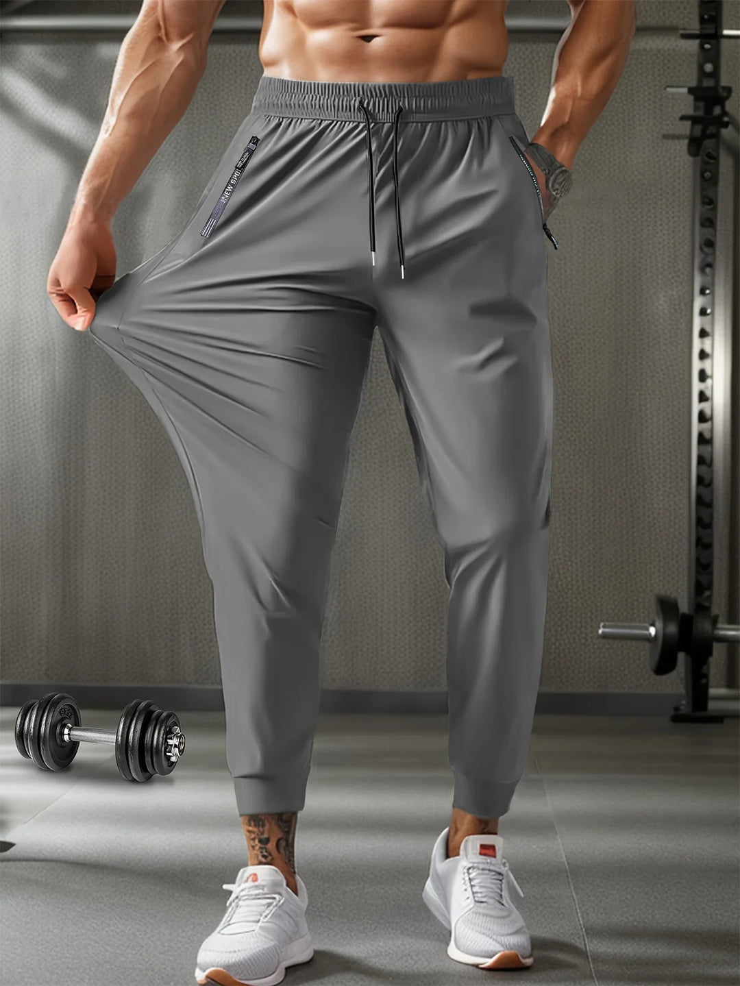 Man wearing gray stretchy gym jogger pants and white sneakers in a fitness gym