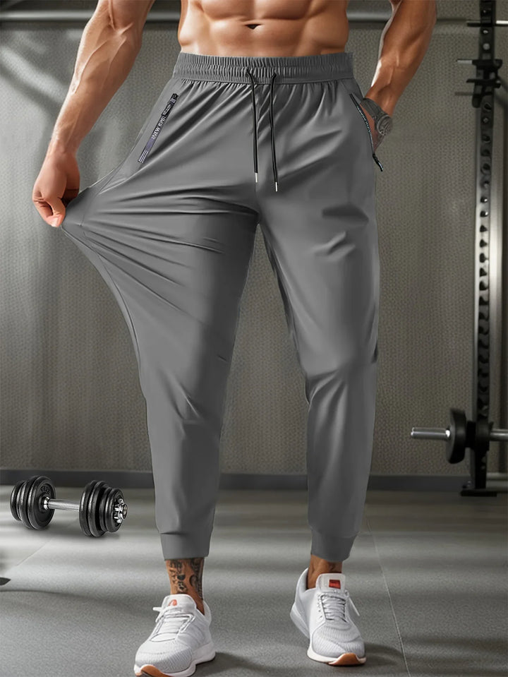 Man wearing gray stretchy gym jogger pants and white sneakers in a fitness gym