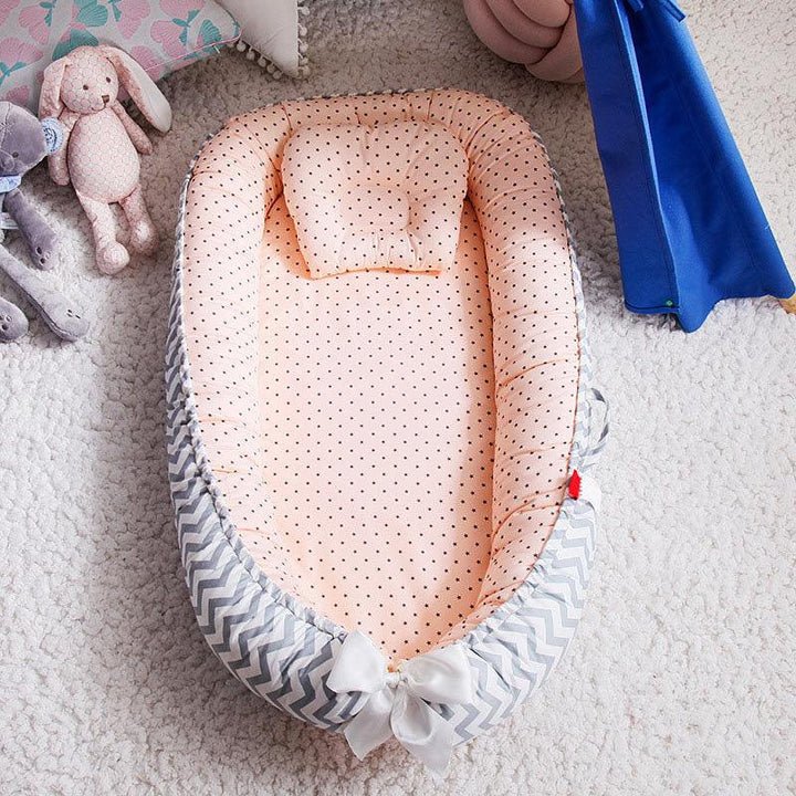 Baby nest bed with pink polka dot interior and gray chevron exterior on white carpet