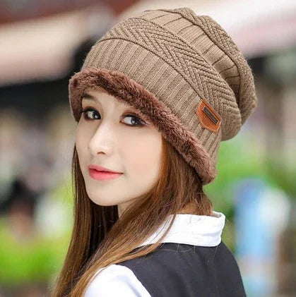 Woman wearing a brown knitted beanie with faux fur trim outdoors, with long hair and natural makeup