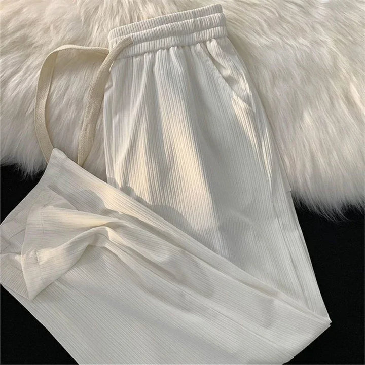 Beige ribbed knit casual sweatpants with drawstring waistband on furry white surface