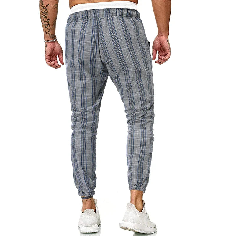 Back view of man wearing gray and blue plaid jogger pants with elastic cuffs and white sneakers