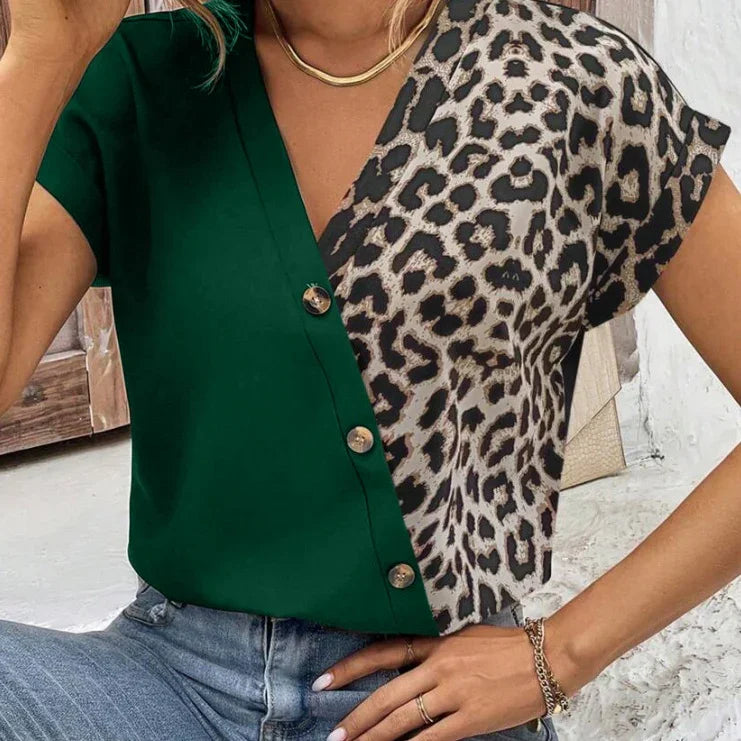 Woman wearing a green and leopard print short sleeve button-up top with gold necklace and bracelets