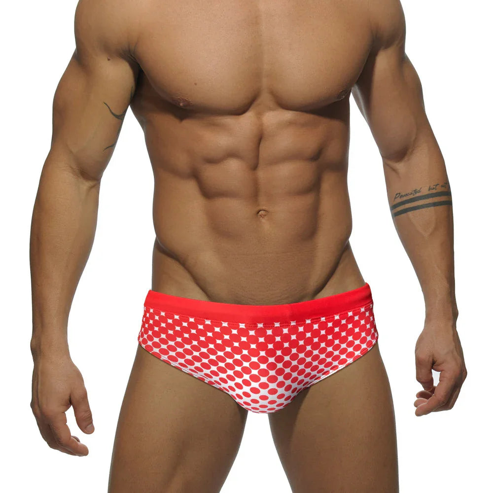 Muscular man wearing red and white graphic swim briefs against white background