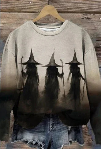 Beige and black ombre sweatshirt with three shadowy witch figures wearing pointed hats, paired with distressed denim shorts